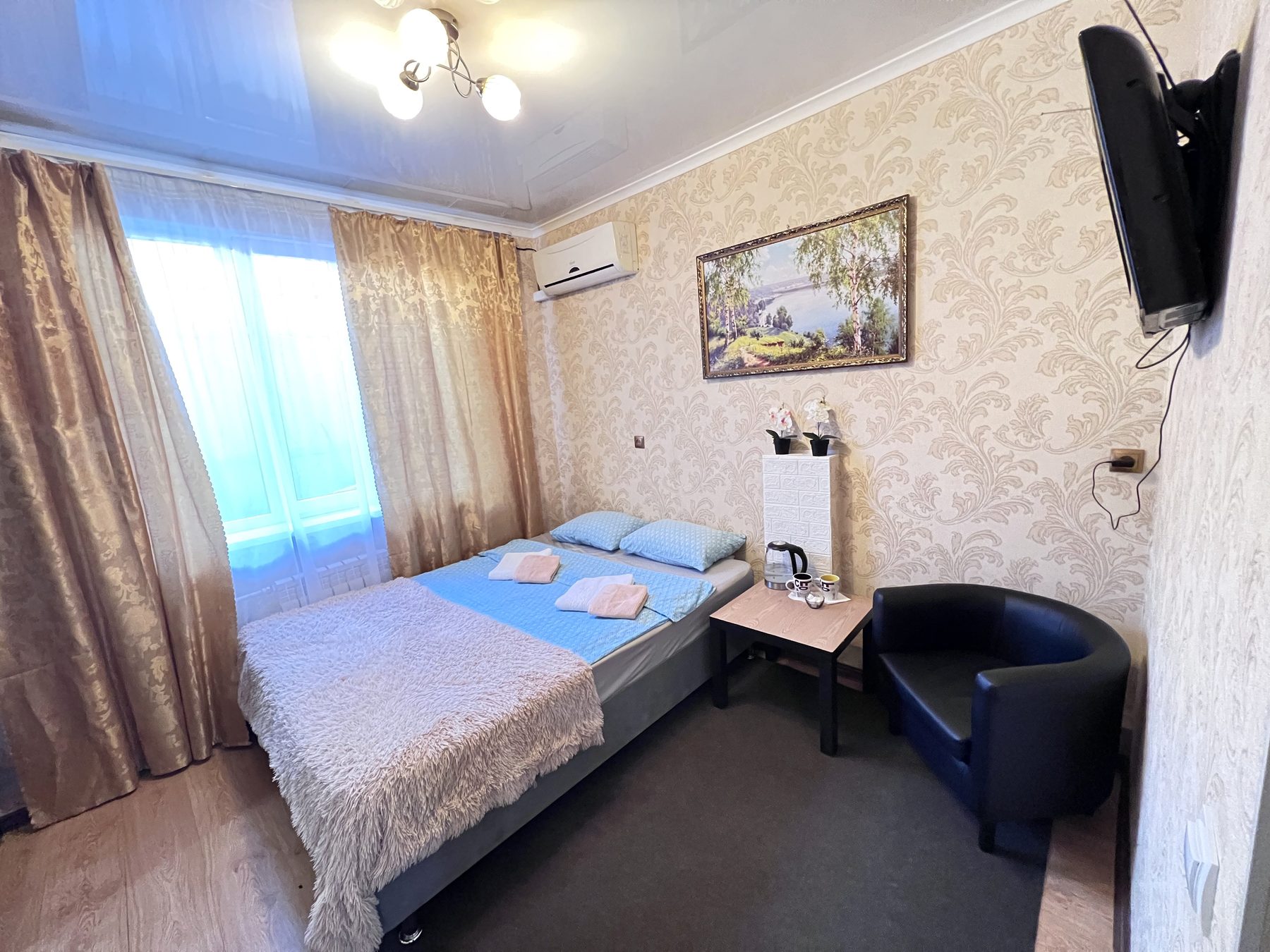 Светлый номер с двуспальной кроватью, креслом и телевизором